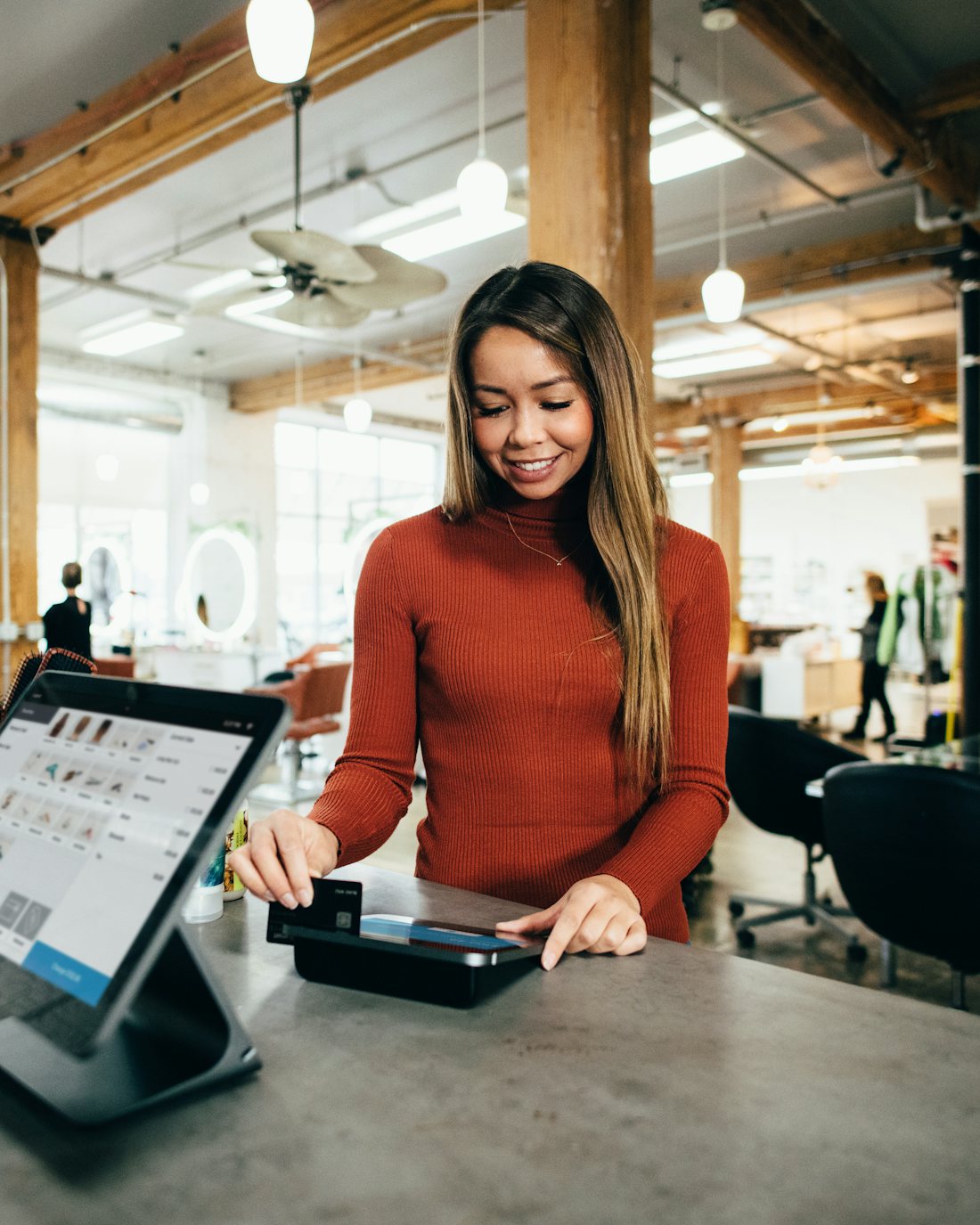 A shop owner serving a customer at the counter of a bright local store