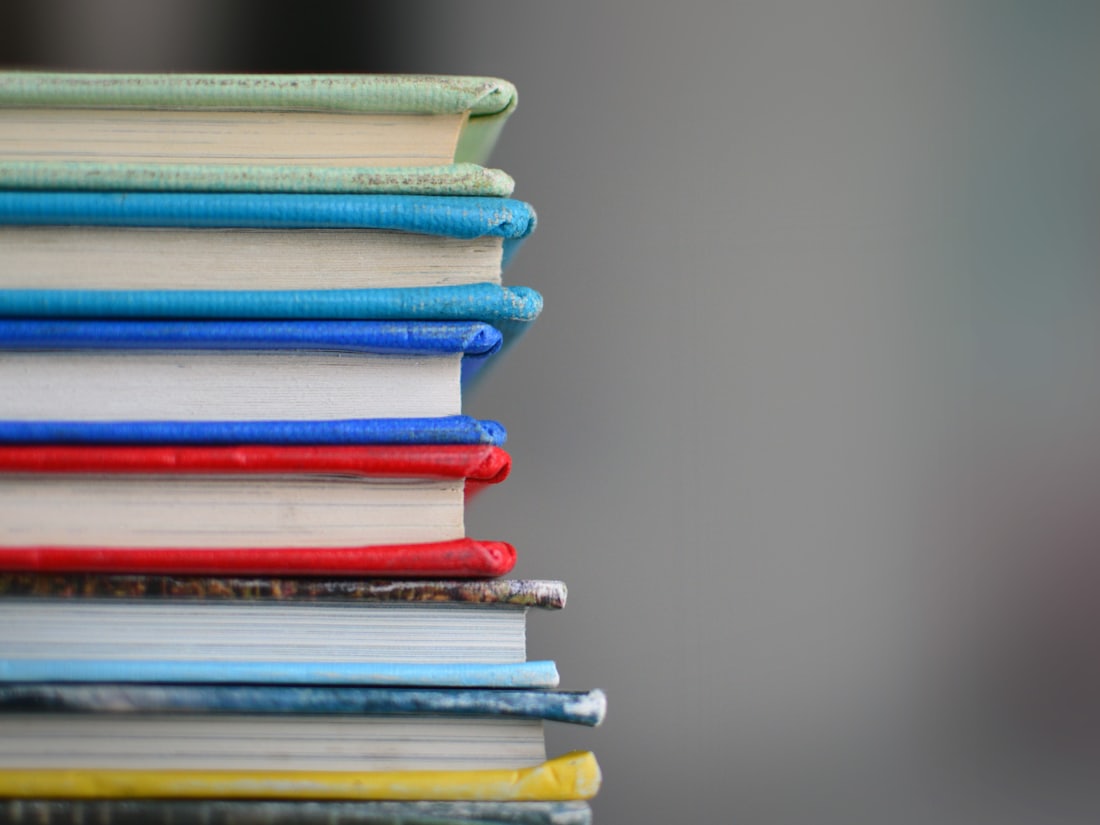 A stack of school textbooks in assorted colours